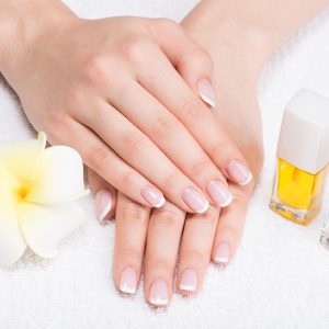 Woman in a nail salon receiving manicure by a beautician. Beauty treatment concept.